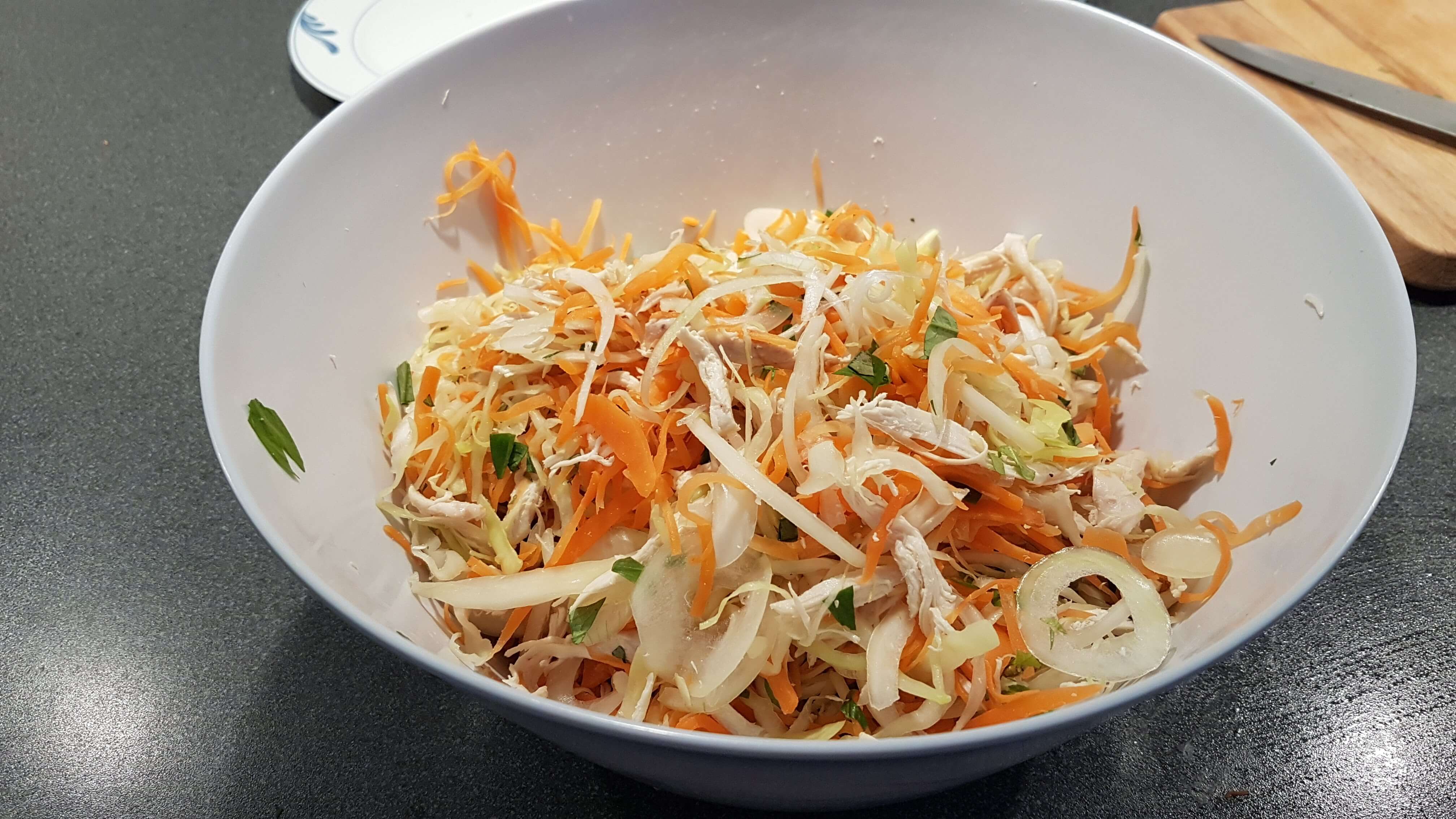 Alle ingredienserne (gulerødder, hvidkål, løg, vietnamesisk koriander og kylling) blandet sammen efter sylten er hældt fra.