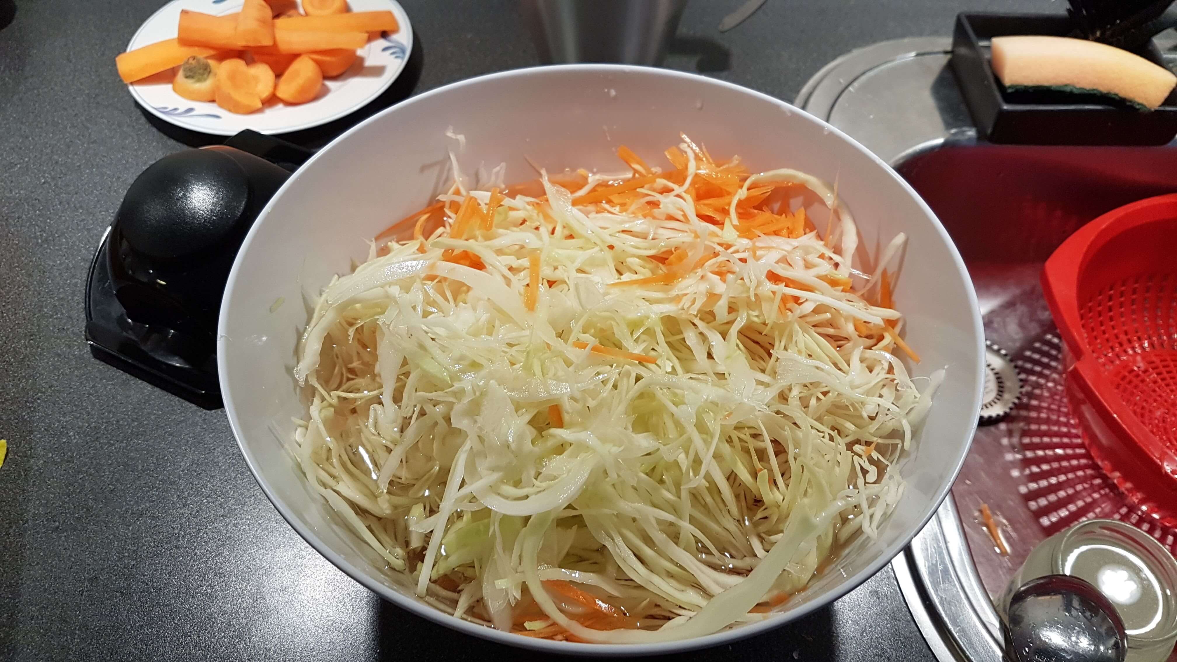 Bland hvidkål og gulerødderne i en stor skål med sylten.