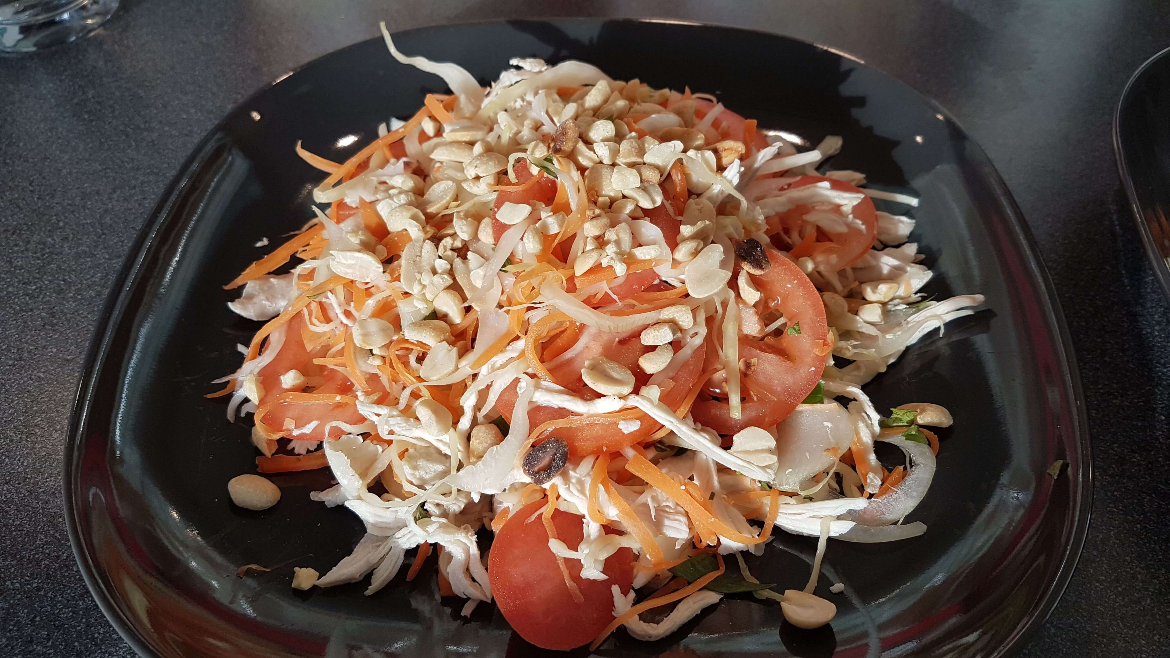 Færdig blandet salat med ristede jordnødder og tomat.